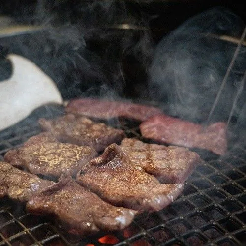 Beef rib finger cooking on a grill over white charcoal
