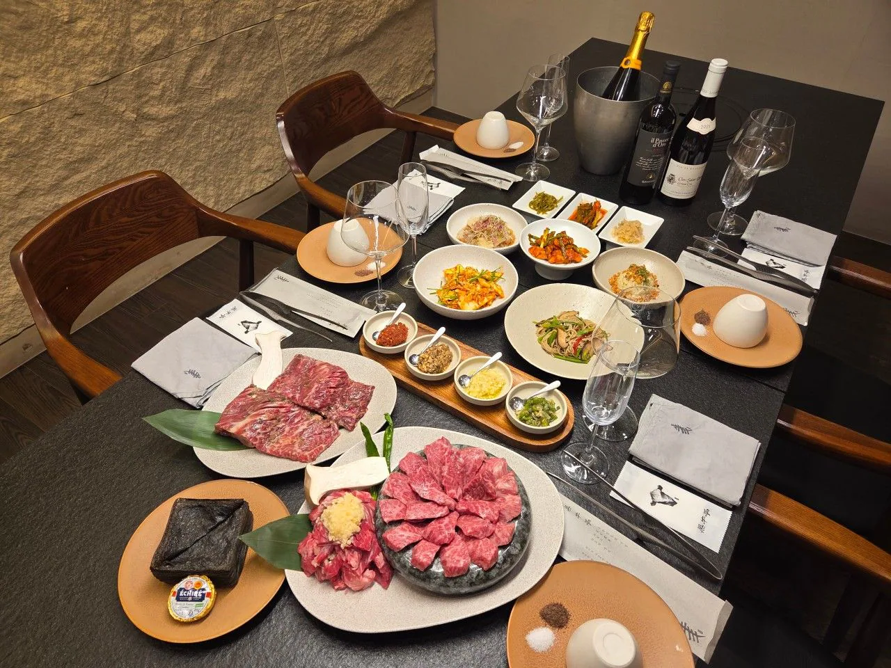 A table set with wine, side dishes and beef in a private room at Heukwoojeong