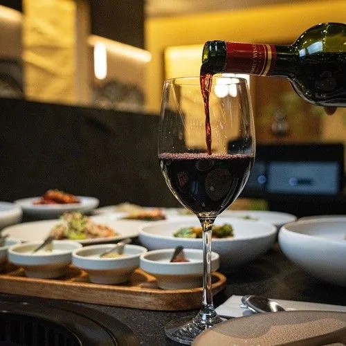 Red wine being poured into a glass, with side dishes